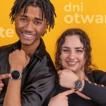 students on yellow background pointing to their watches