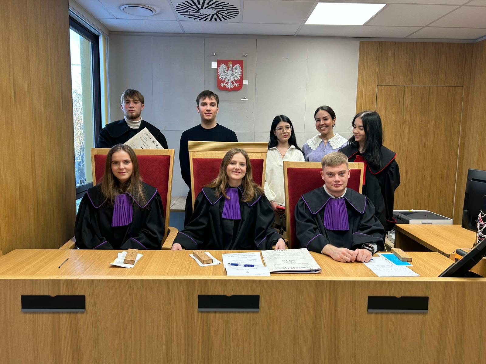 studenci prawa na Uniwersytecie VIZJA, stoją w togach na sali sądowej