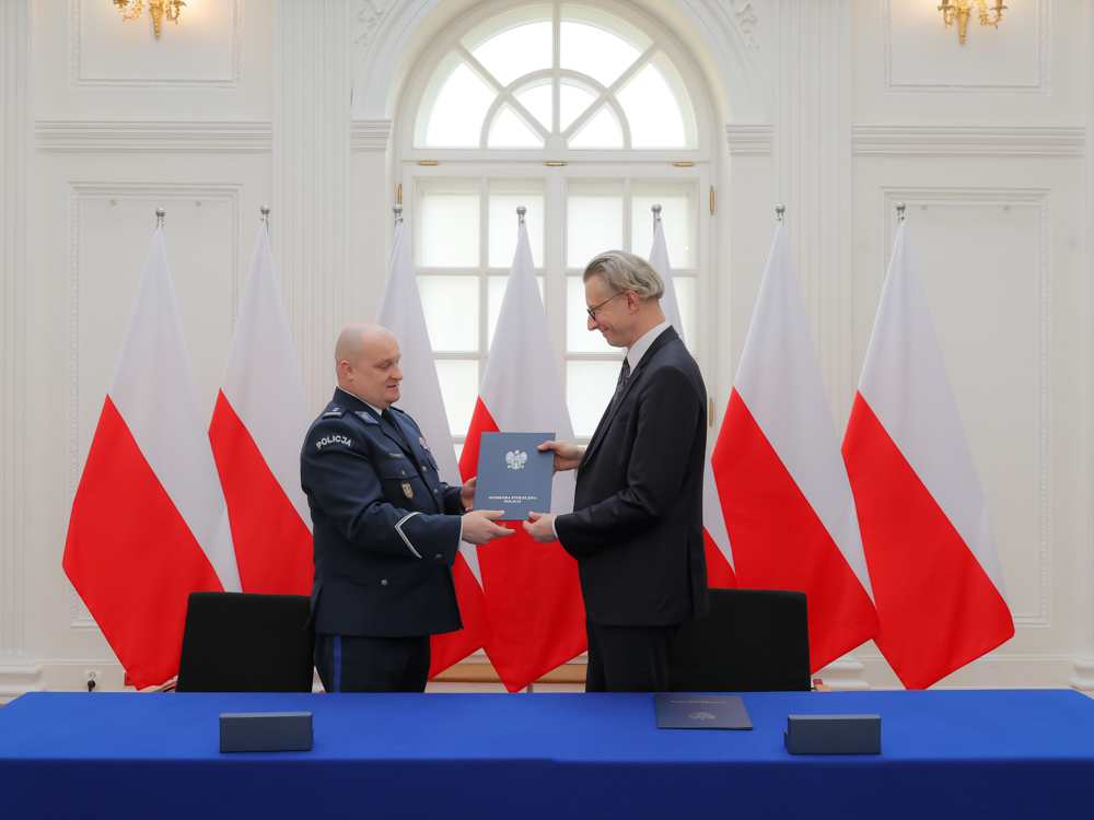 dwóch mężczyzn przy stole prezydialnym prezentuje podpisany dokument o porozumieniu